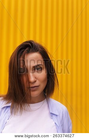 Portrait Attractive Woman On Yellow Background. She Look On Camera Pretentious Or Arrogantly.