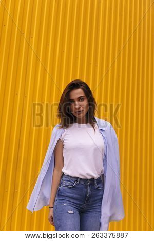 Portrait Attractive Woman On Yellow Background. She Look On Camera Pretentious Or Arrogantly.