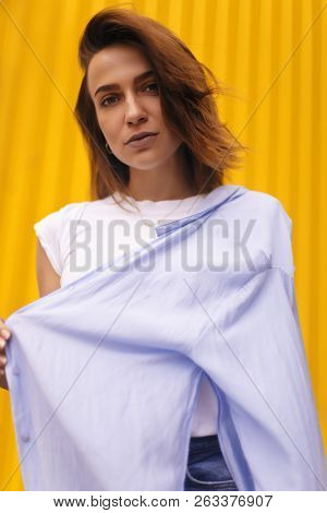 Portrait Attractive Woman On Yellow Background. She Look On Camera Pretentious Or Arrogantly.