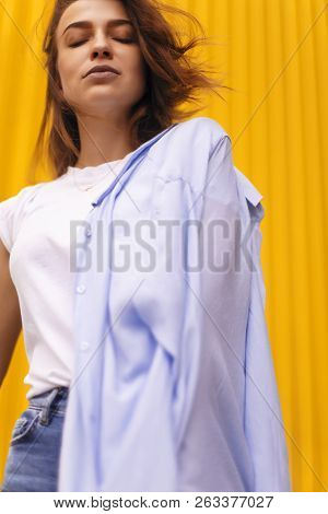 Portrait Attractive Woman On Yellow Background. She Look On Camera Pretentious Or Arrogantly.