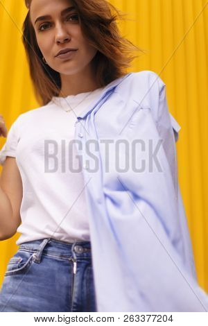 Portrait Attractive Woman On Yellow Background. She Look On Camera Pretentious Or Arrogantly.
