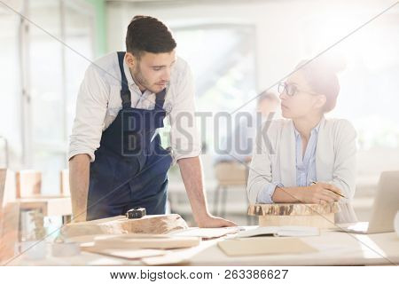 Female expert and male engineer discussing characteristics of materials for cabinetmaking