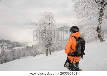 Man Standing With The Snowboard In The Mountain And Looking Into A Distance In The Popular Tourist R