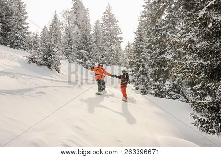 Two Snowboarders Running Down The Hill Holding Hands In The Popular Tourist Resort In Goderzi, Georg