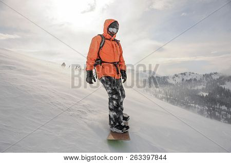 Man Riding Down The Mountain Hill On The Snowboard On The Background Of Sky In The Mountain Tourist 