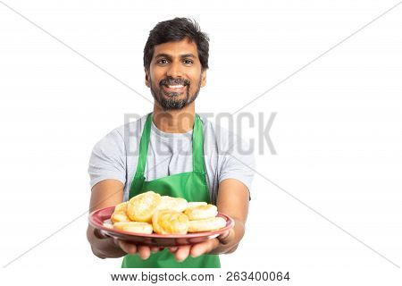Friendly Indian Male Employee At Supermarket Or Hypermarket Offering Donuts On Plate Isolated On Whi