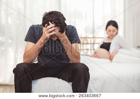 Worried Stress Man Sitting On Bed With Hand On Forehead In Bedroom In Serious Mood Emotion With Preg