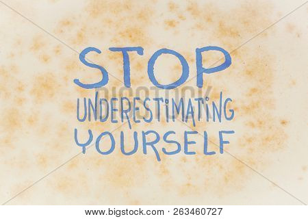 Stop underestimating yourself - inspirational handwriting on an old yellowed paper