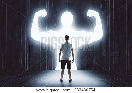Young Guy With Muscly Arms In Concrete Interior. Confidence And Power Concept