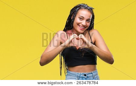 Young braided hair african american with pigmentation blemish birth mark over isolated background smiling in love showing heart symbol and shape with hands. Romantic concept.
