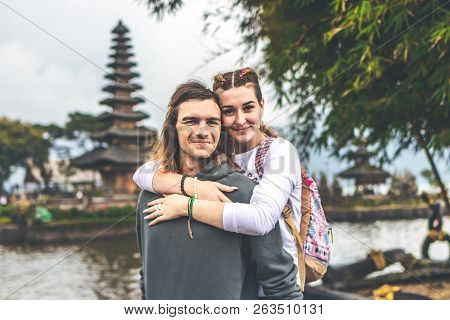 Young Romantic Couple Of Trourists On The Ulan Danu Temple Background. Bali Island.