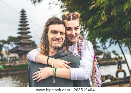 Young Romantic Couple Of Trourists On The Ulan Danu Temple Background. Bali Island.