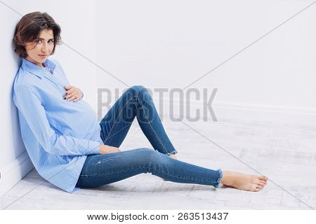 A beautiful pregnat woman sitting in a studio. Motherhood. Fashion for pregnant women