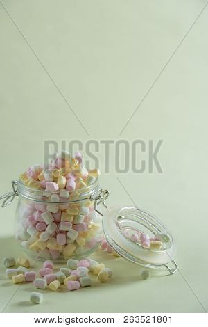 Multicolored Fluffy Marshmallow Overspill From A Big Jar On A Green Vibrant Background