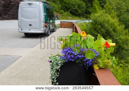 Camper Van With Storage Bag On Parking Area At Svandalsfossen Waterfall In Norway. Flowers Decoratio