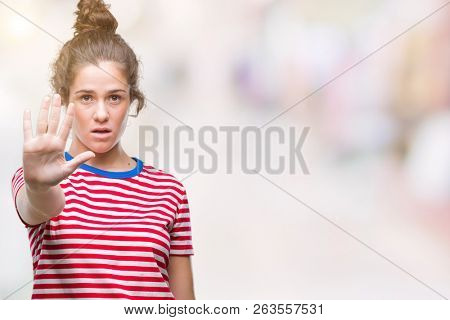 Beautiful brunette curly hair young girl wearing casual look over isolated background doing stop sing with palm of the hand. Warning expression with negative and serious gesture on the face.