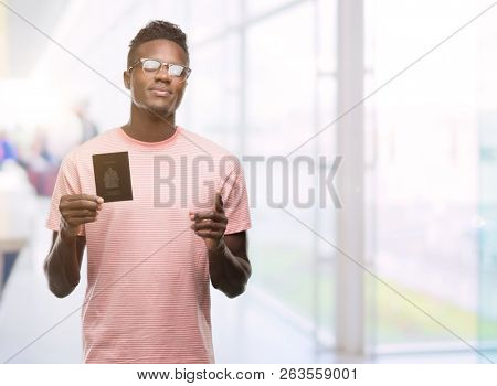 Young african american man holding canadian passport surprised with an idea or question pointing finger with happy face, number one