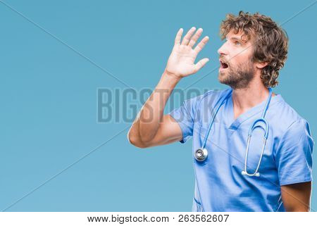 Handsome hispanic surgeon doctor man over isolated background shouting and screaming loud to side with hand on mouth. Communication concept.