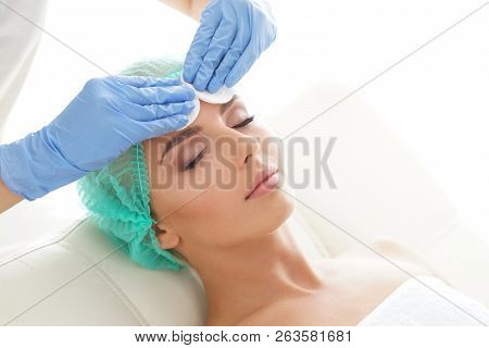 Cosmetologist Cleaning Face Of A Young Woman With A Cotton Pads. Removing Cosmetics With Hygienic Di