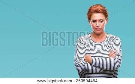 Atrractive senior caucasian redhead woman over isolated background skeptic and nervous, disapproving expression on face with crossed arms. Negative person.