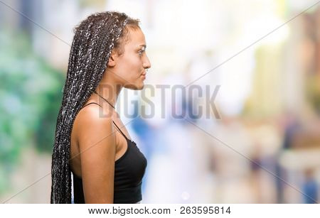 Young braided hair african american with pigmentation blemish birth mark over isolated background looking to side, relax profile pose with natural face with confident smile.