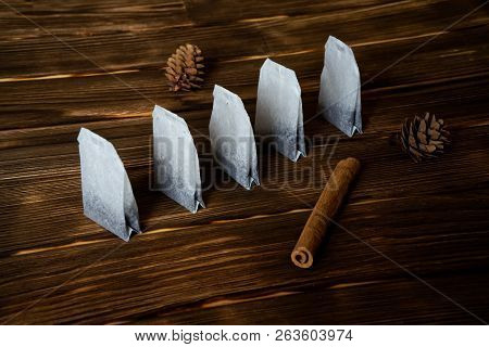 Tea Bags Lie On A Wooden Surface With Cinnamon And Pine Cones. Health And Nature.