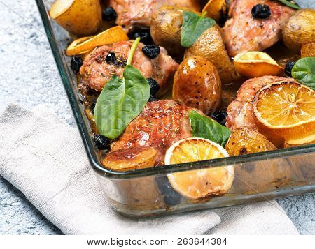 Close Up View Of Chicken Thighs With Potatoes, Lemon And Black Olives, Cooked In Oven On Gray Concre