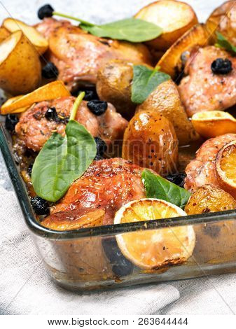 Close Up View Of Chicken Thighs With Potatoes, Lemon And Black Olives, Cooked In Oven On Gray Concre