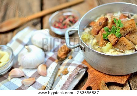 Detail Of Garlic Soup In An Old Saucepan, Fresh Garlic Bulbs, Cloves, Colored Pepper, Wooden Spoon, 