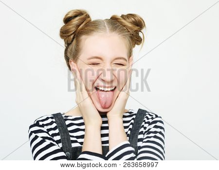 funny girl showing her tongue while posing against studio background
