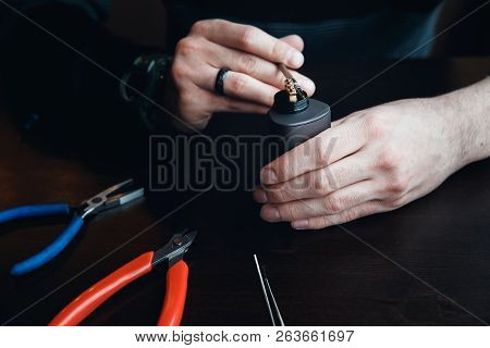 Male Master Installs A Coyle. Spiral For Electronic Evaporator And Cigarette. Vape, Vaping. Pliers, 