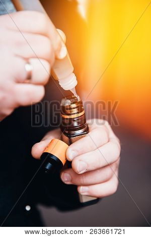 Close-up Of A Man Dripping A Fragrant Liquid On A Cotton Wool Electronic Cigarette. Nichrome Heated.