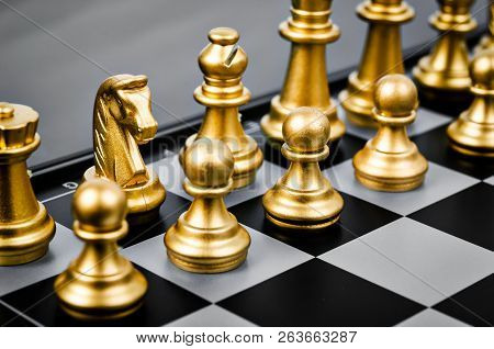 Gold Chess Pieces On A Black And White Chess Board.