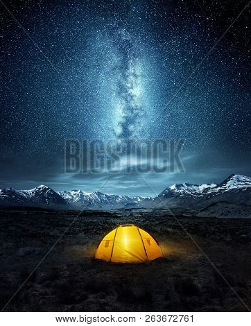 Camping In The Wilderness. A Pitched Tent Under The Glowing  Night Sky Stars Of The Milky Way With S