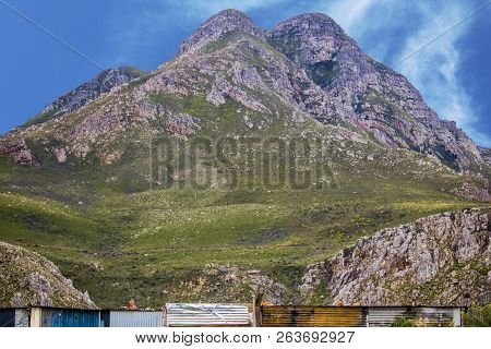 Wide Shot Of Shack Homes In Township Below Massive Mountain In Kleinmond, Western Cape, South Africa