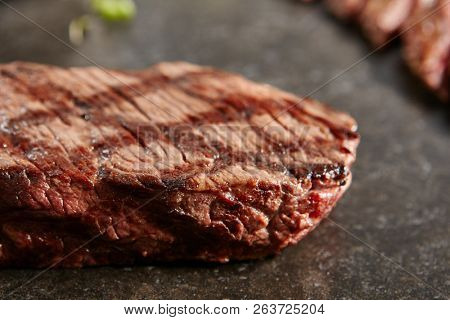 Hot Grilled Whole Denver Steak on Black Stone Background. Fresh Juicy Medium Rare Beef Grillsteak. Barbecue Meat Close Up