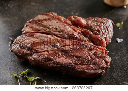 Thick Slices of Hot Grilled Whole Alternative Steak on Black Stone Background. Fresh Juicy Medium Rare Beef Grillsteak. Barbecue Meat Close Up