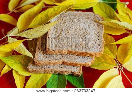 Pieces Of Bread Among The Yellow Autumn Leaves. Harvest Time.