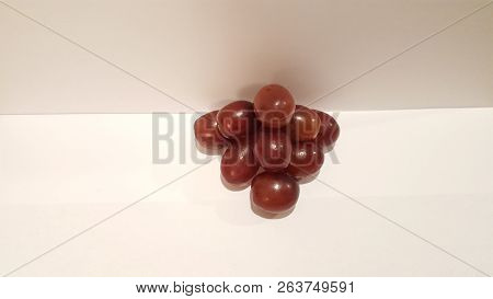 Red Grapes Stacked Into A Pyramid On White Background.