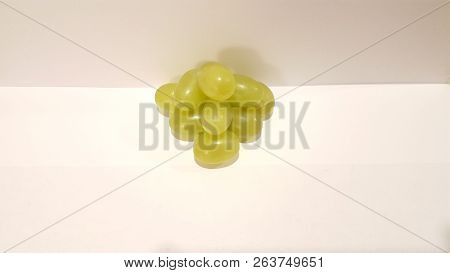 Green Grapes Stacked Into A Pyramid On White Background.