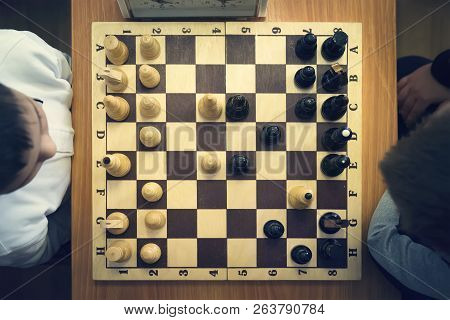 Kids Playing Chess Sitting On Wooden Floor. Game, Education, Leisure Concept. Top View.