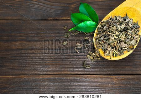 Dried Tea Leaves In Wooden Spoon With Green Leaves Close Up On A Old Dark Wooden Background, Copy Sp