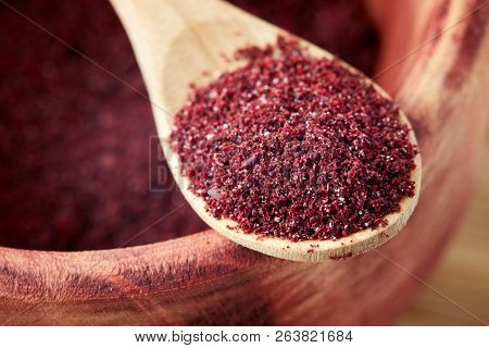 Close Up Of Ground Sumac Spice Powder In Wooden Spoon