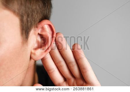 Man With Hearing Problem On Grey Background. Close Up.