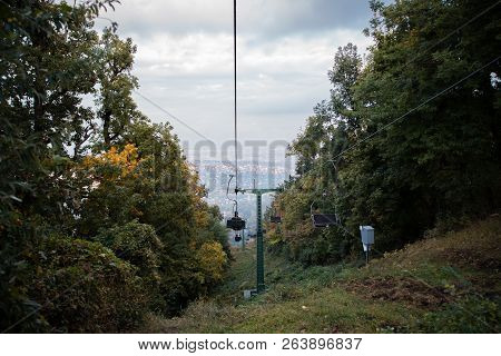 A Cabin Of Cableway Above The Autumn Forest, City Budapest In The Background