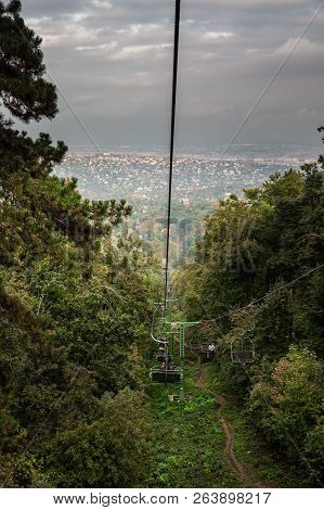 A Cabin Of Cableway Above The Autumn Forest, City Budapest In The Background