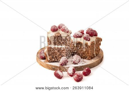 Chocolate Cake Decorated By White Glaze And Fresh Berries Of Raspberry Is Strewed With Icing Sugar L