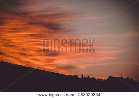 Some Intense Red And Orange Clouds Reach The Shadows Of The Gound While Sunset Arrives