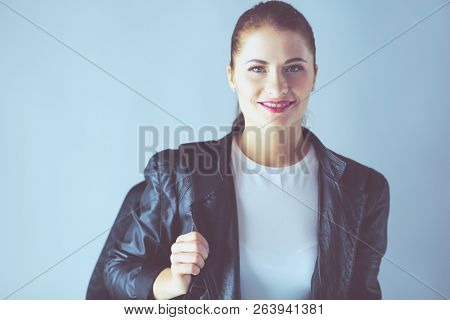 Portrait Of Beautiful Young Brunette Woman In Stylish Black Jacket On Gray.