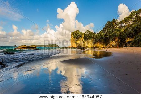 Evening tide on the beach of Cathedral Cave. Coast of the North Island of New Zealand. Stunning sunset on the beach. Concept of active and ecological tourism